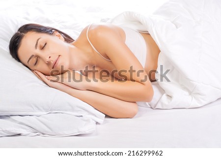 Attractive young woman sleeping in white bed