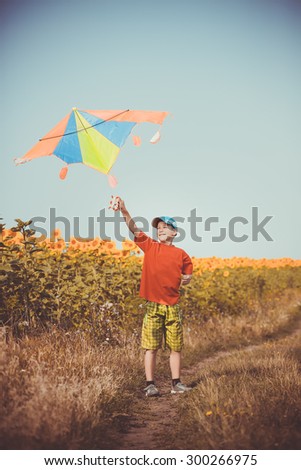Boy running across the field with kite flying over his head