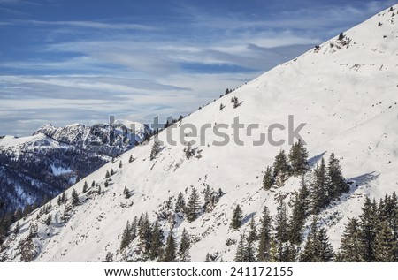 Hiking in the winter hills and mountains. Outdoor activity on a clear and sunny day. Vast forests and meadows covered with snow. Dramatic scenery in the Julian Alps.