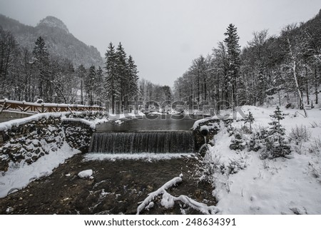 Beautiful winter scenery by the lake and the River. Heavy snow and blizzard is giving the scenery a unique appearance and look. Waterfall from the bridge.