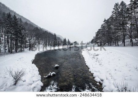 Beautiful winter scenery by the lake and the River. Heavy snow and blizzard is giving the scenery a unique appearance and look. Frozen river and rocks on the coast.