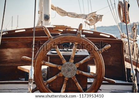 Closeup of a vintage hand wheel on a wooden sailing yacht. Yachting, helm of old wooden sailboat in port of sailing, rope, steering wheel, details of yacht.