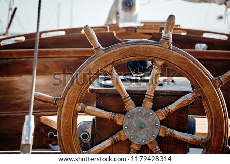 Closeup of a wheel and deck of a wooden antique sailing yacht.