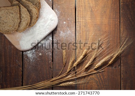 Rustic bread and wheat on an old vintage planked wood table. Dark moody background with free text space