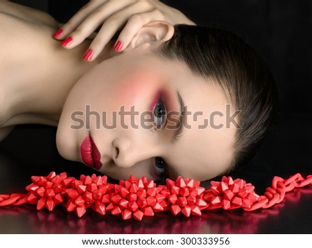 Beautiful model with a bright make-up and red jewelry.  Jewelry and Beauty. Fashion photo