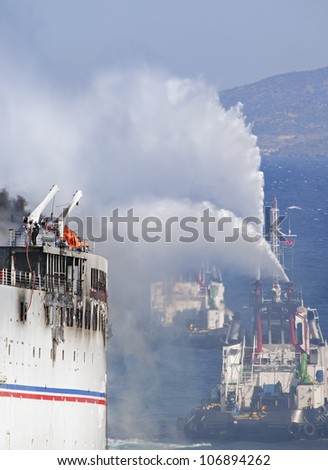 Burning ship and  Fire Fighting Boat sprays jets of water