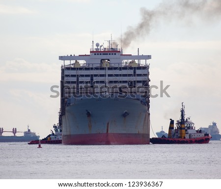 Tugboat towing a large cargo ship in port.