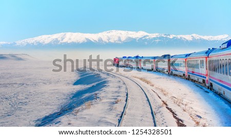 Red passenger diesel train moving at the terminal. Snow covered railway tracks - East express between Ankara and Kars - Turkey
