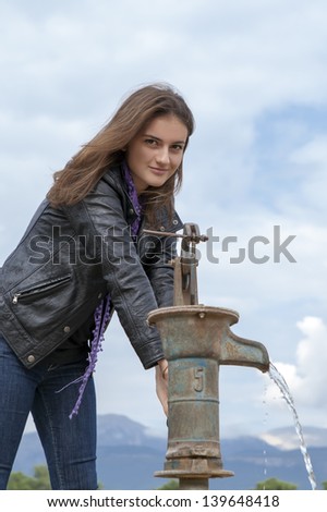sympathetic girl pumping hand water pump - retro style