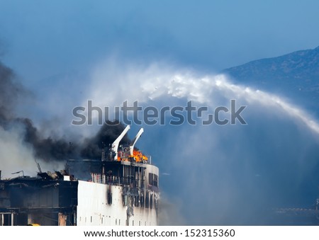 Burning ship and Fire Fighting Boat sprays jets of water