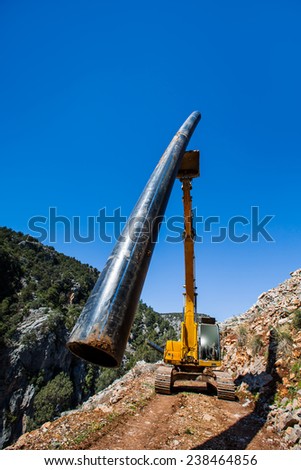 Loader delivering pipe for installation in hill