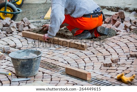 Construction worker fixing the pavestone on the road