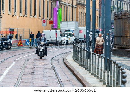 MILAN, ITALY - MARCH 25, 2015: Young beautiful woman traveling by a motorbike in Milan