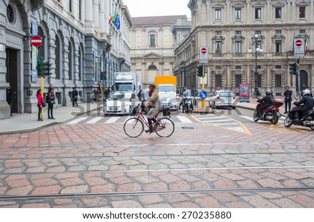 MILAN, ITALY - MARCH 24, 2015: Woman riding bike with  bag on the road