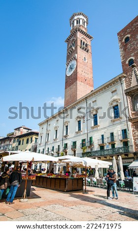 VERONA, ITALY -  MARCH 23, 2015:people and tourists strolling in the day market in the square of Verona in the background the tower Lamberti.