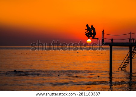Young boys jumping in water from pier