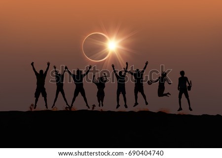 Silhouette of friends jumping at Solar Eclipse \