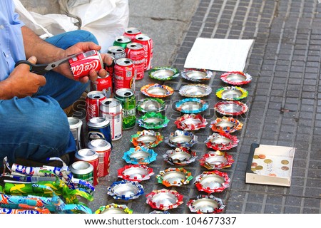 MADRID - JUNE 3: Unidentified man makes ashtrays out of aluminum cans for money in the street, June 3, 2012 in Madrid, Spain. A Caritas report shows 22% of households in Spain below the poverty line.