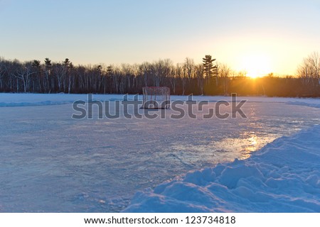 Ice hockey rink on frozen lake at sunset
