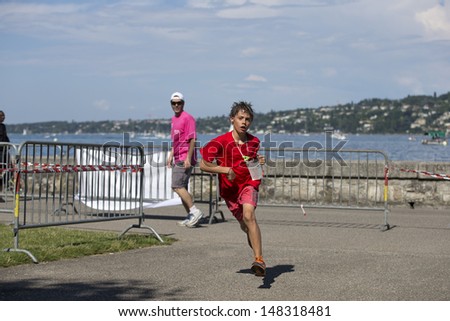 GENEVA - JULY 20: Unidentified young athlete competes in the running section in the 2013 ITU Kidsathlon race, July 20, 2013 in Geneva, Switzerland.