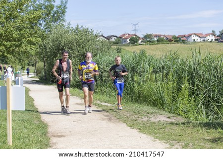 MACHILLY, FRANCE JULY 6, 2014: Unidentified athletes participate in the running race of the Lake Machilly Triathlon which is part of the TriSaleve of Annemasse organization.