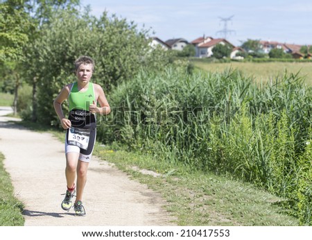MACHILLY, FRANCE JULY 6, 2014: Unidentified young athlete participates in the running race of the Lake Machilly Triathlon which is part of the TriSaleve of Annemasse organization.