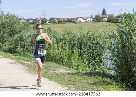 MACHILLY, FRANCE JULY 6, 2014: Unidentified athlete participates in the running race of the Lake Machilly Triathlon which is part of the TriSaleve of Annemasse organization.