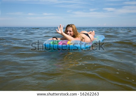 Beautiful girl swimming on air-mattress in sea