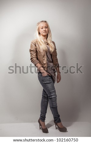 Full length portrait of sexy model wearing jeans and beige coat
