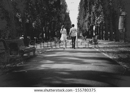 Black And White Photo Of Couple Holding Hands And Walking In Park