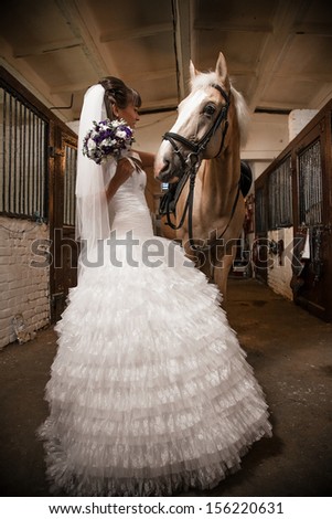 Beautiful bride holding horse by rein