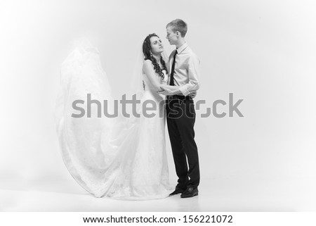 Black and white photo of newlywed couple hugging with veil lifted up