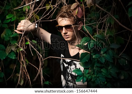 Fashionable man posing in bushes