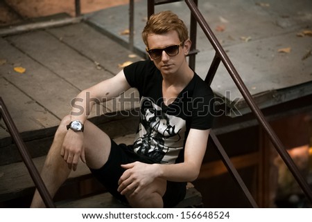 Sexy man posing on rooftop near railing