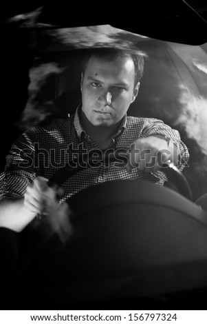 Black and white portrait of handsome driver holding steering wheel