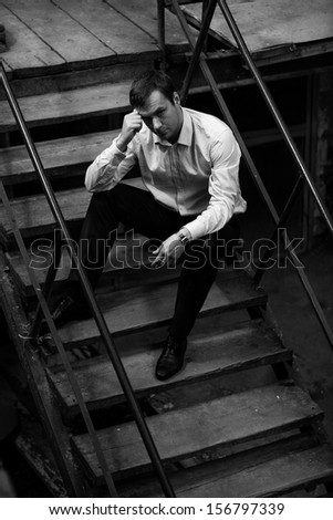 Black and white photo of man sitting on steps