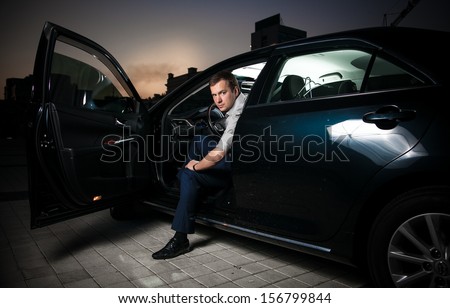 Sexy man sitting in car with front door open