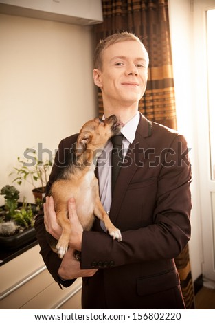 Small dog licking man in dark suit