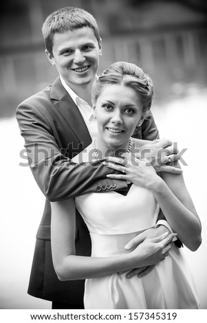 Black and white portrait of groom hugging his bride from back