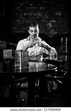 Black and white portrait of man smoking at the table