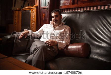 Portrait of rich man sitting on vintage leather sofa