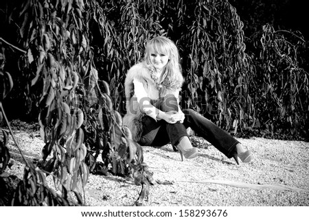 Black and white photo of sexy blonde girl sitting under tree in park