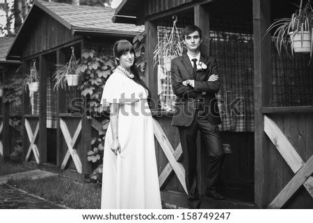 Black and white photo of sexy bride and handsome groom standing close to each other in wooden alcove