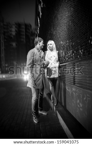 Black and white photo of couple in love walking on street at night