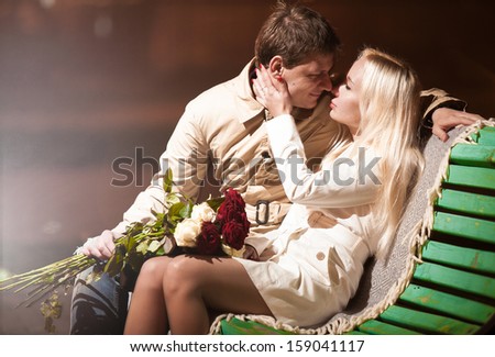 Beautiful young couple in love sitting on bench at night