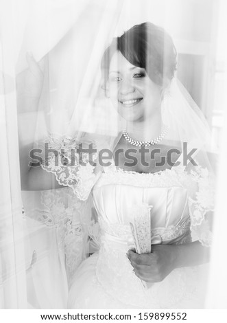 Black and white portrait of smiling bride standing behind window with reflections