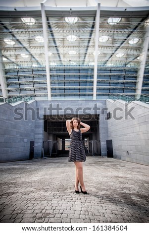 Sexy young girl posing against big stadium entrance