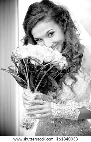 Black and white portrait of married bride holding flowers and smelling them