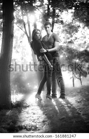 Black and white photo of couple standing in park at dusk
