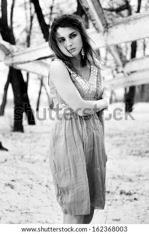 Black and white photo of woman in dress getting cold outdoors